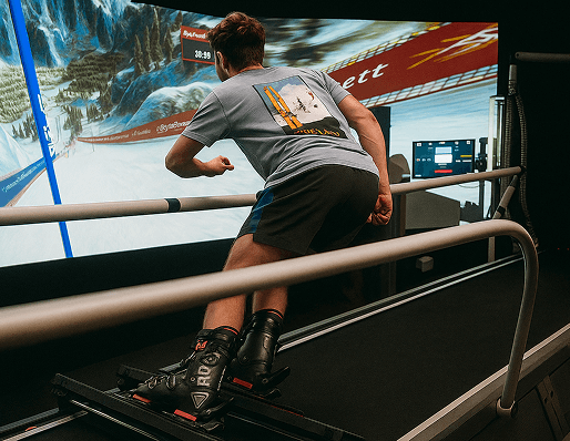 Man practicing turns on a ski simulator at Home Mountain — guided coaching that brings the mountain indoors.