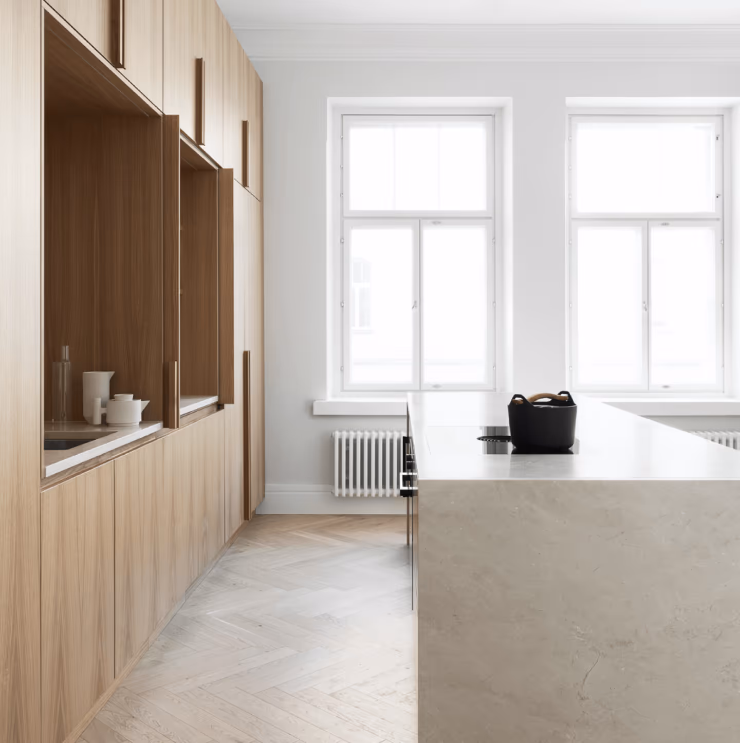 Pehmeästi valaistettu vaalea keittiö ruskeilla kaapeilla