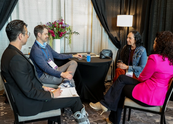 Attendee using a tablet while colleagues meet in a hotel lounge