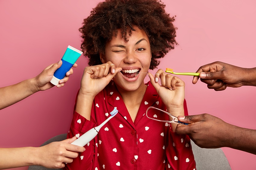 A dental hygienist performing a teeth cleaning with a polishing tool on a patient's teeth.