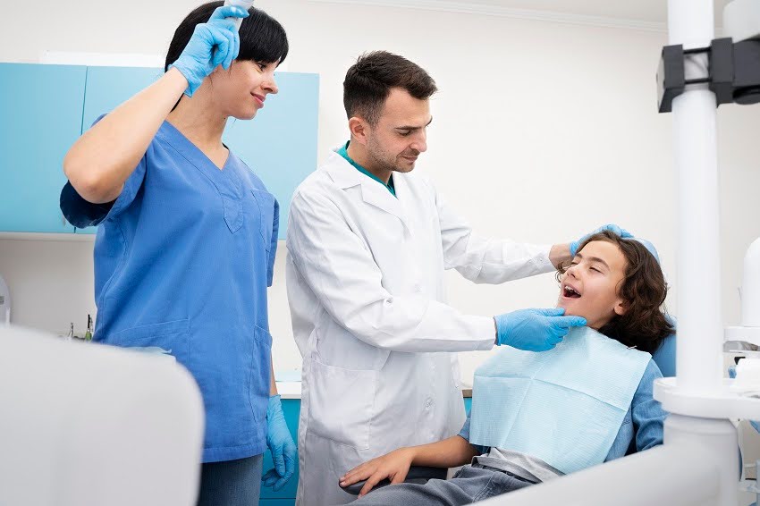 Dentist and dental assistant performing dental bonding, tooth fillings, and teeth bonding procedure on a young patient to enhance their smile.