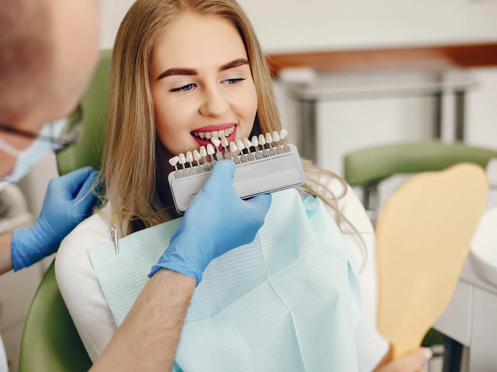 Dentist performing dental bonding treatment, showing tooth fillings and teeth bonding options to a patient while matching veneers for a natural smile.
