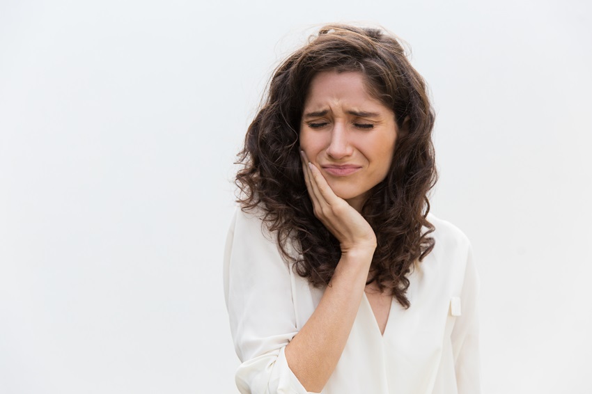 A frustrated woman suffering from a toothache requiring a root canal procedure.