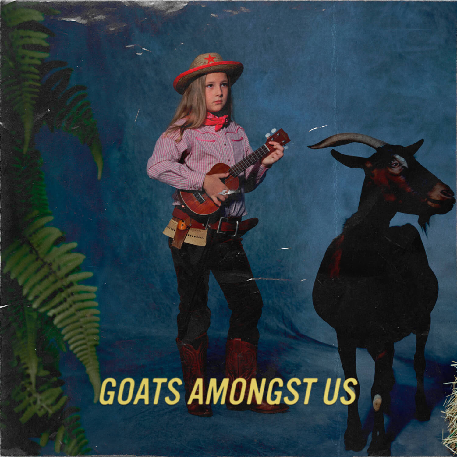 Young Country Girl, wearing a Cowboy Outfit and i holding a small guitare. On her right we see a black goat and on the left a big fern in the foreground. The background is a vintage background we use to see in the 1980's in studios. The image is uncanny and we can read on the image: Goats Amongst Us