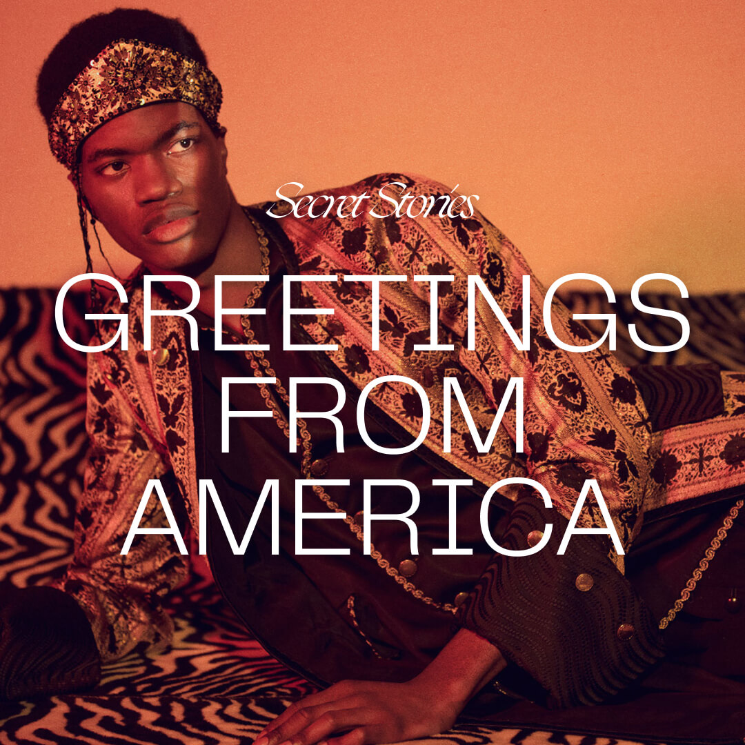 an exotically dressed black man laying on his side facing the camera with text overlay reading Secret Stories, Greetings from America