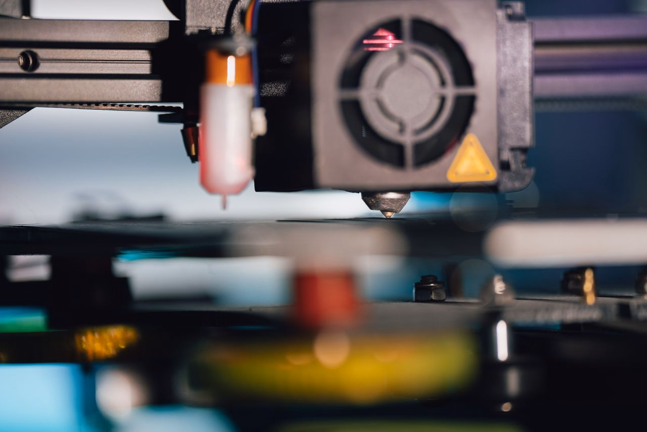 Macro shot of a 3D printer nozzle during printing.