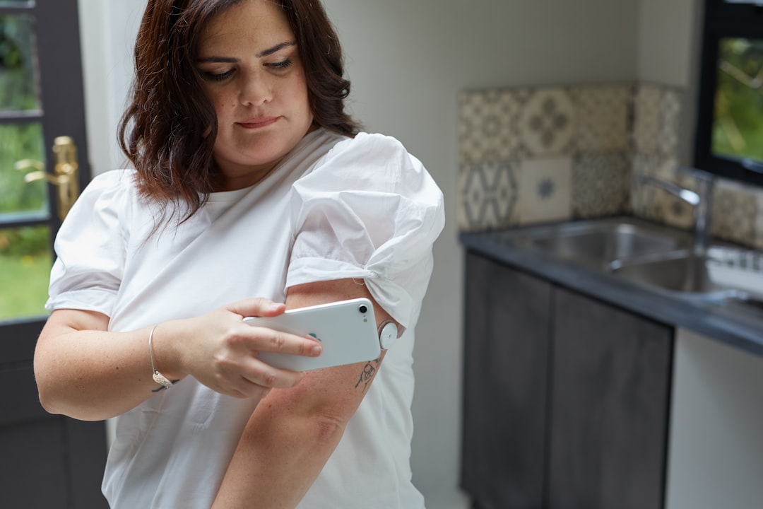 Woman takes a picture of her arm with a phone.