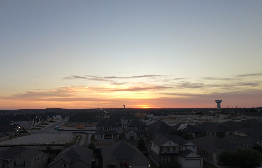 Sunset over a suburban neighborhood with distant hills.