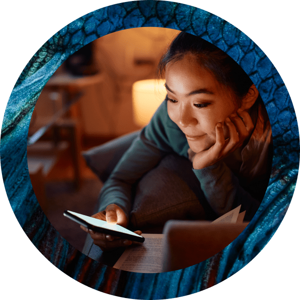A person with dark hair rests their head on one hand while looking at a glowing smartphone in a dimly lit room. The portrait is framed by a thick blue textured circular border.