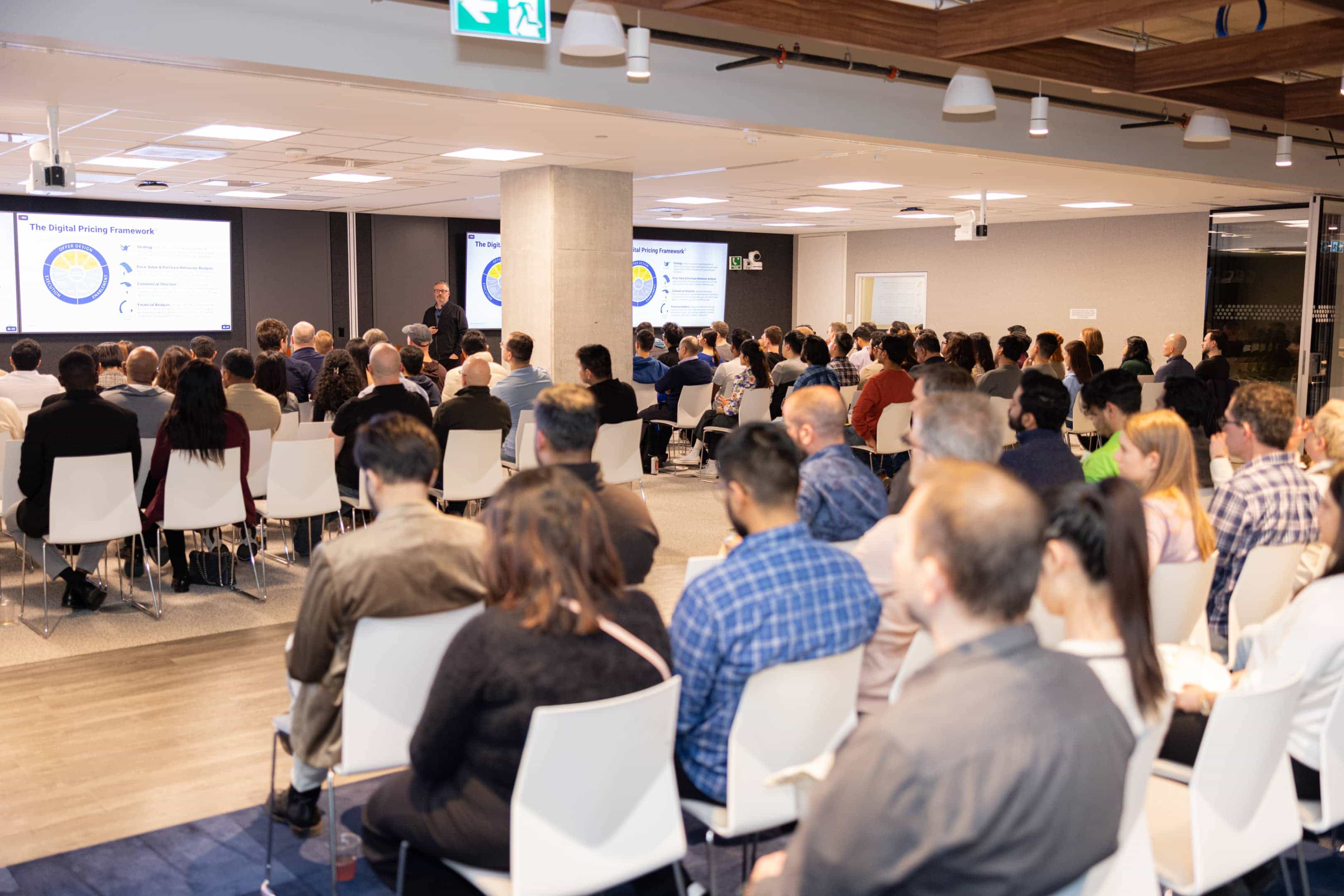 TPMA EVENTS  group of people seated in white chairs attending a presentation on digital pricing framework in a modern conference room.