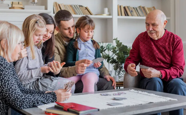 Cette image montre 3 générations d'une famille jouant aux cartes ensemble