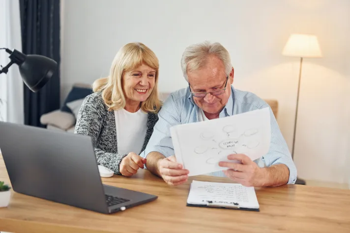 Cette image montre un couple de seniors examinant des documents administratifs