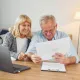 Cette image montre un couple de seniors examinant des documents administratifs