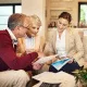Cette image montre un couple de seniors avec leur conseillère, examinant des documents