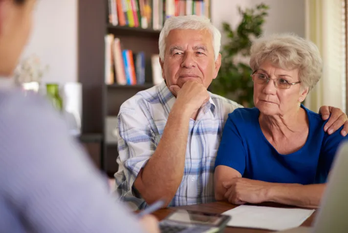 Cette image montre un couple senior écoutant leur conseiller