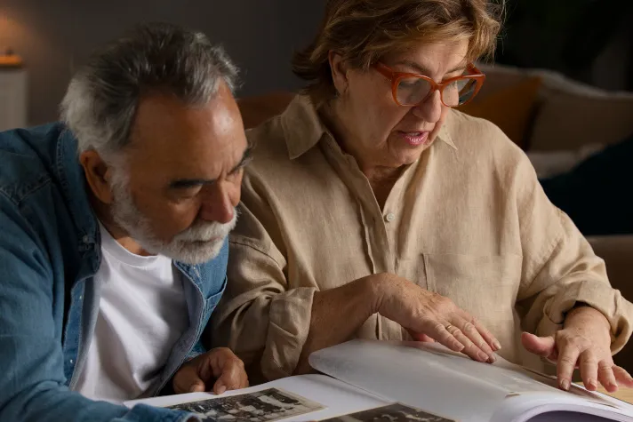 Cette image montre un couple senior contemplant un album photo