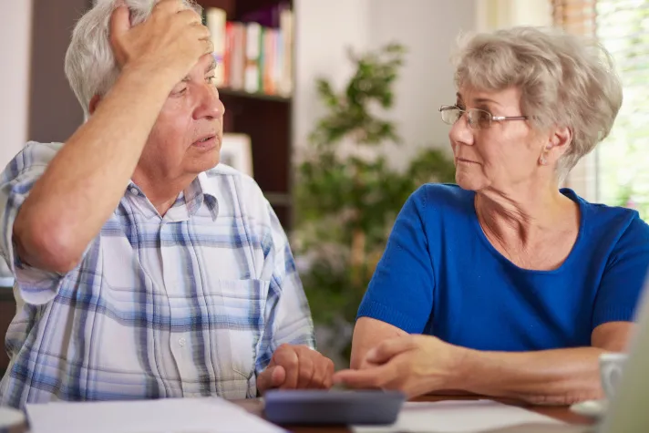 Cette image montre un couple de personnes âgées examinant des documents