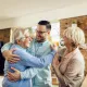 Cette image montre un couple de personnes âgées, faisant l'accolade à une personne plus jeune. 