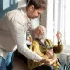 Cette image montre un homme âgée et son petit fils qui s'occupe de lui