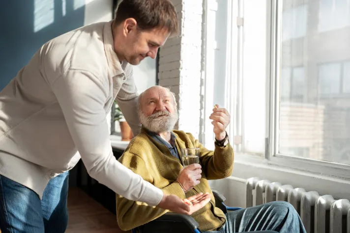 Cette image montre un homme âgée et son petit fils qui s'occupe de lui