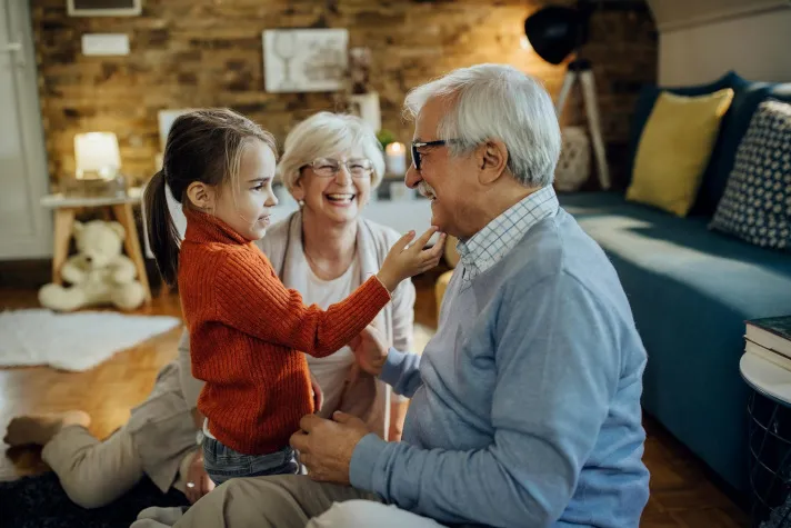 Cette image montre un couple de grands parents avec leur petite fille