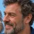 Cette image montre le visage d'un homme senior souriant