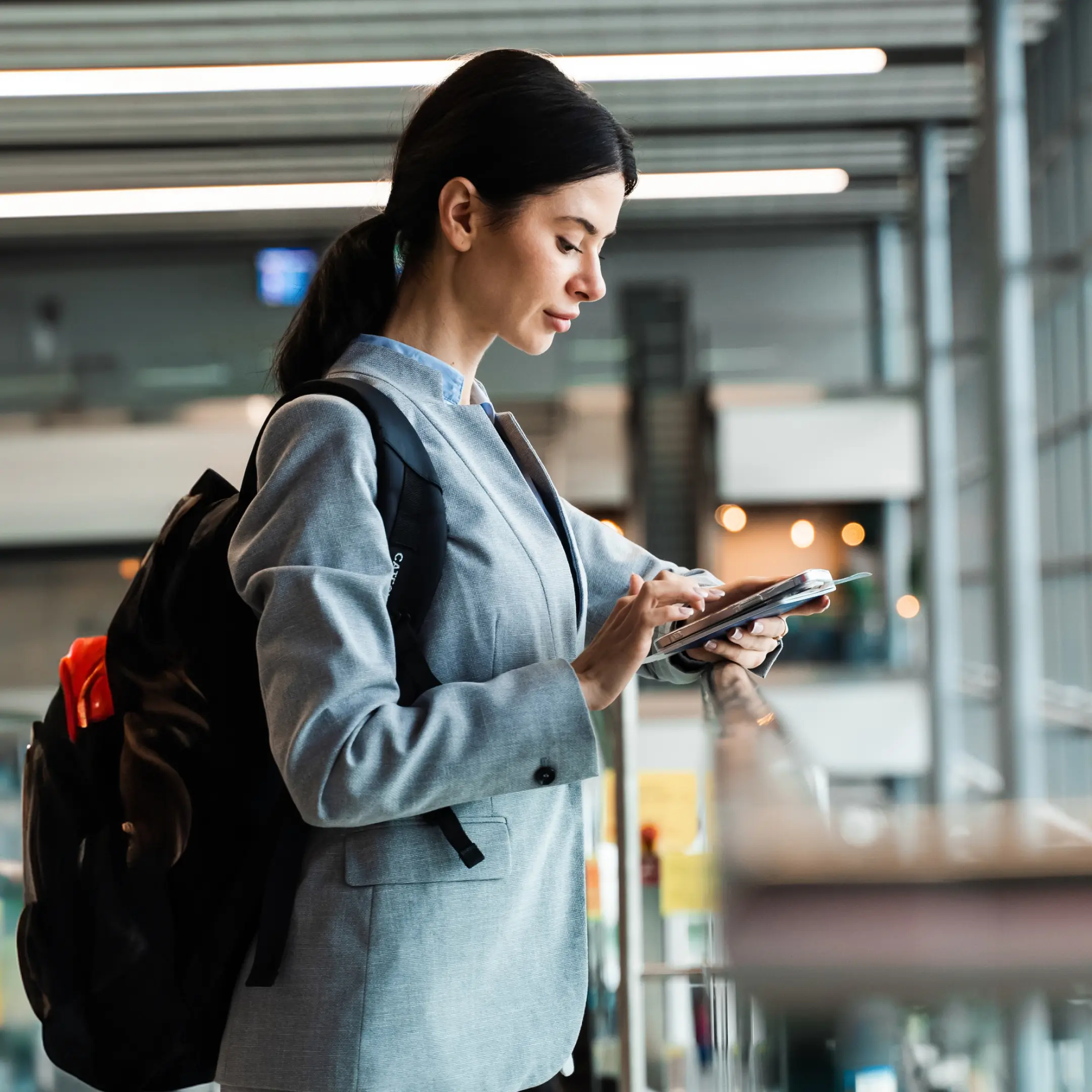 Foto van een luchthavenpassagier die op haar mobiele telefoon kijkt.