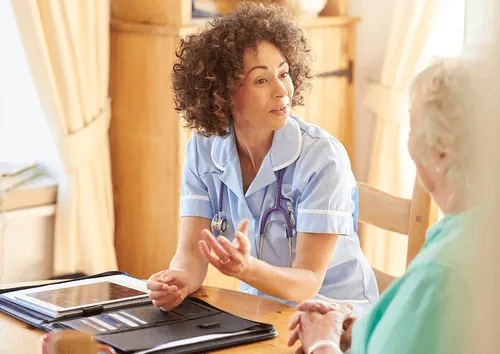 Nurse in uniform consulting with an elderly patient at home