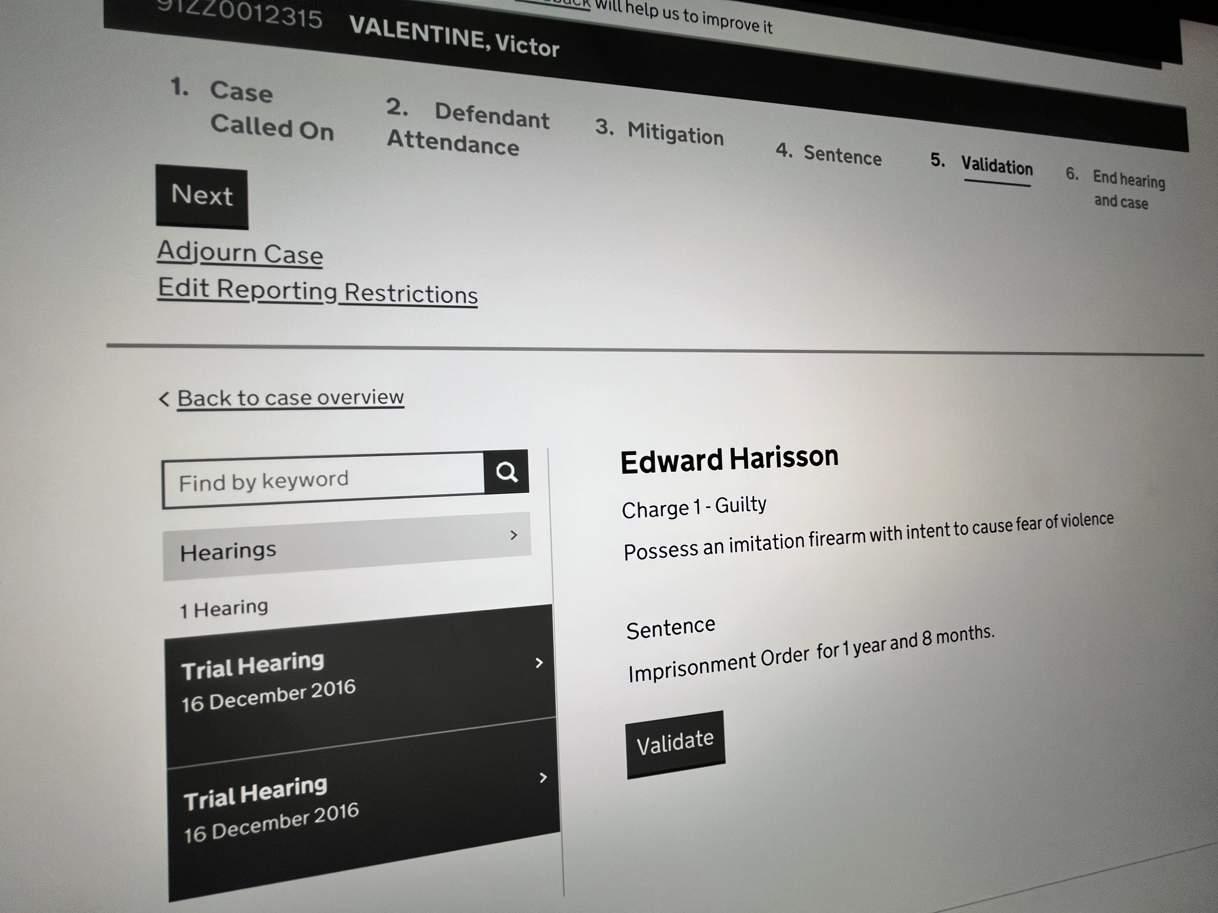 Court case interface showing steps: Case Called On, Defendant Attendance, Mitigation, Sentence, Validation (highlighted), and End hearing and case. To the left, a search box and hearing list with two Trial Hearings dated 16 December 2016. On the right, case details for Edward Harisson: Charge 1 - Guilty for possessing an imitation firearm with intent to cause fear of violence, and a sentence of imprisonment for 1 year and 8 months, with a Validate button below.