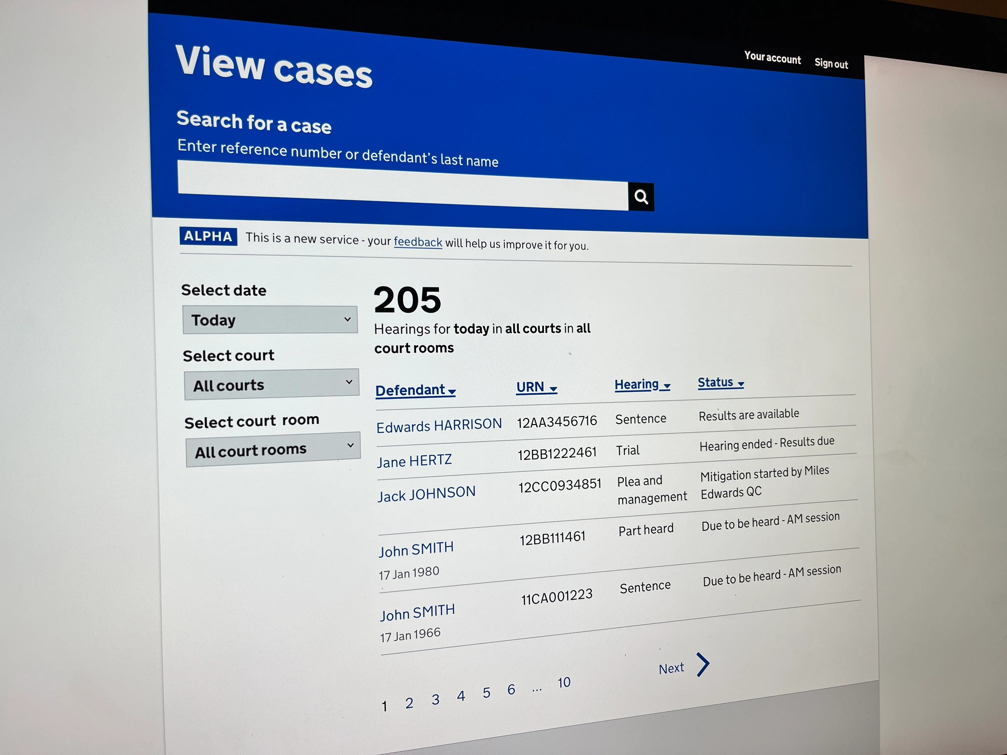 Web page showing a 'View cases' search interface for court hearings with filters for date, court, and court room, displaying 205 hearings today. Below is a table with columns for Defendant, URN, Hearing type, and Status, listing cases for Edwards Harrison, Jane Hertz, Jack Johnson, and two John Smiths with hearing details and statuses such as 'Results are available' and 'Due to be heard - AM session'. Pagination controls with numbers 1 to 10 and a 'Next' arrow are at the bottom.
