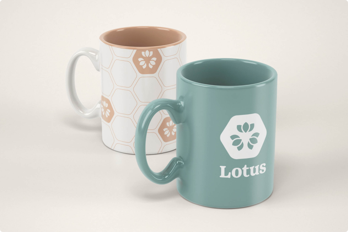 Two ceramic mugs placed on a light surface: one teal mug with a white lotus logo and the word 'Lotus,' and one white mug with a beige hexagonal pattern containing lotus logos.