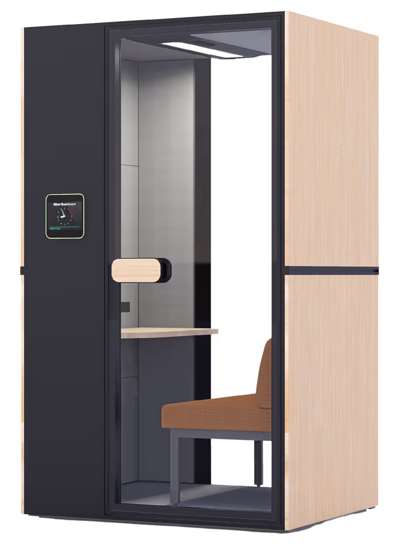 Modern office phone booth with wooden side panels, glass front door, brown cushioned seat, small desk, and digital display panel.