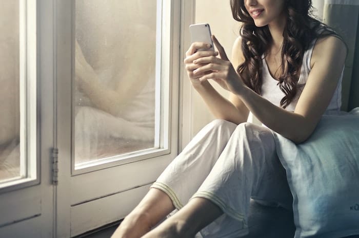 woman sitting by window on phone