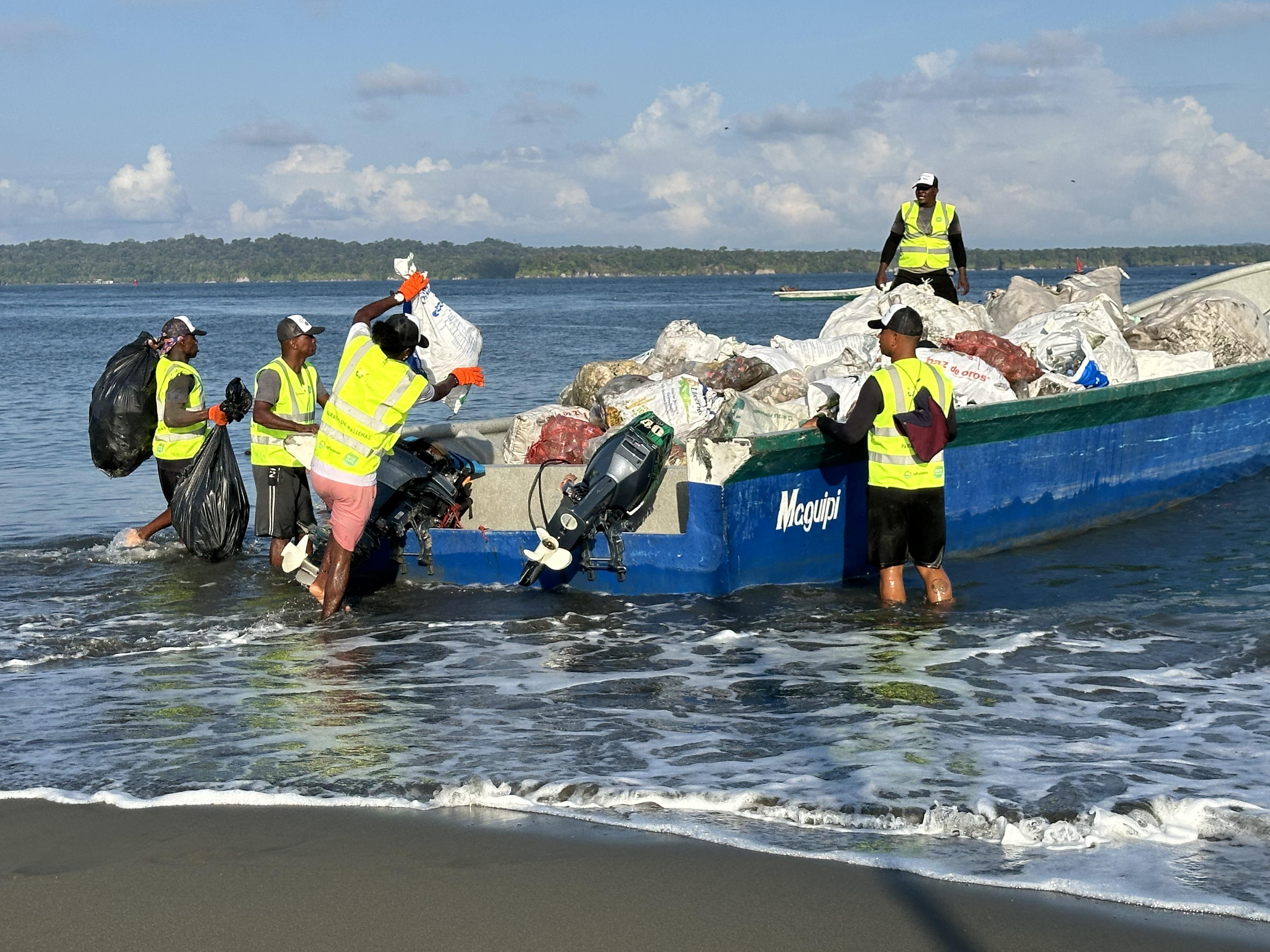 a group of people in vests loading garbage into a boat