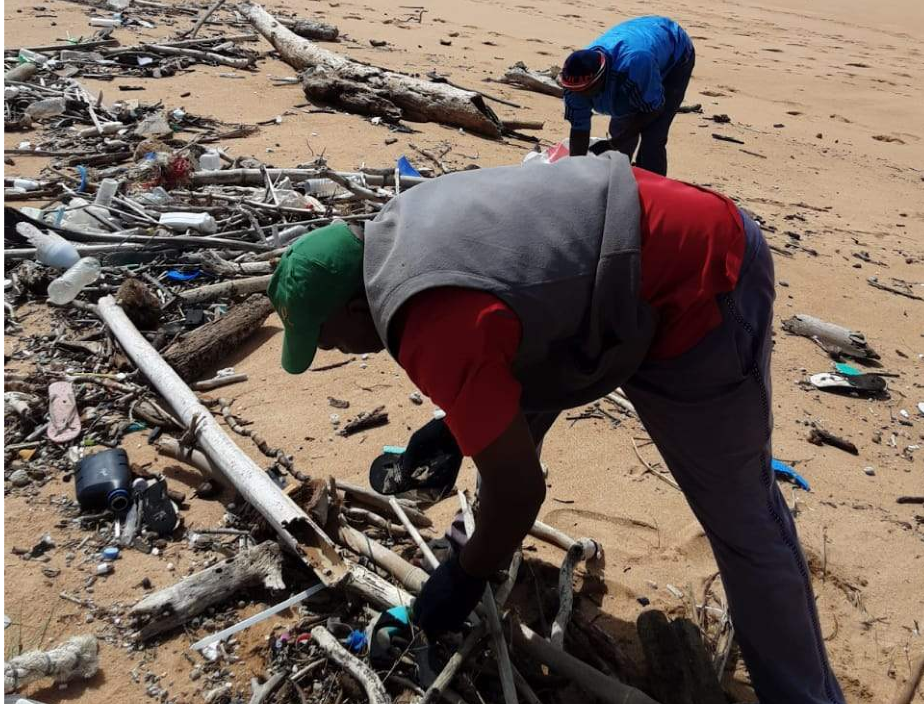 a group of people cleaning up trash on a beach