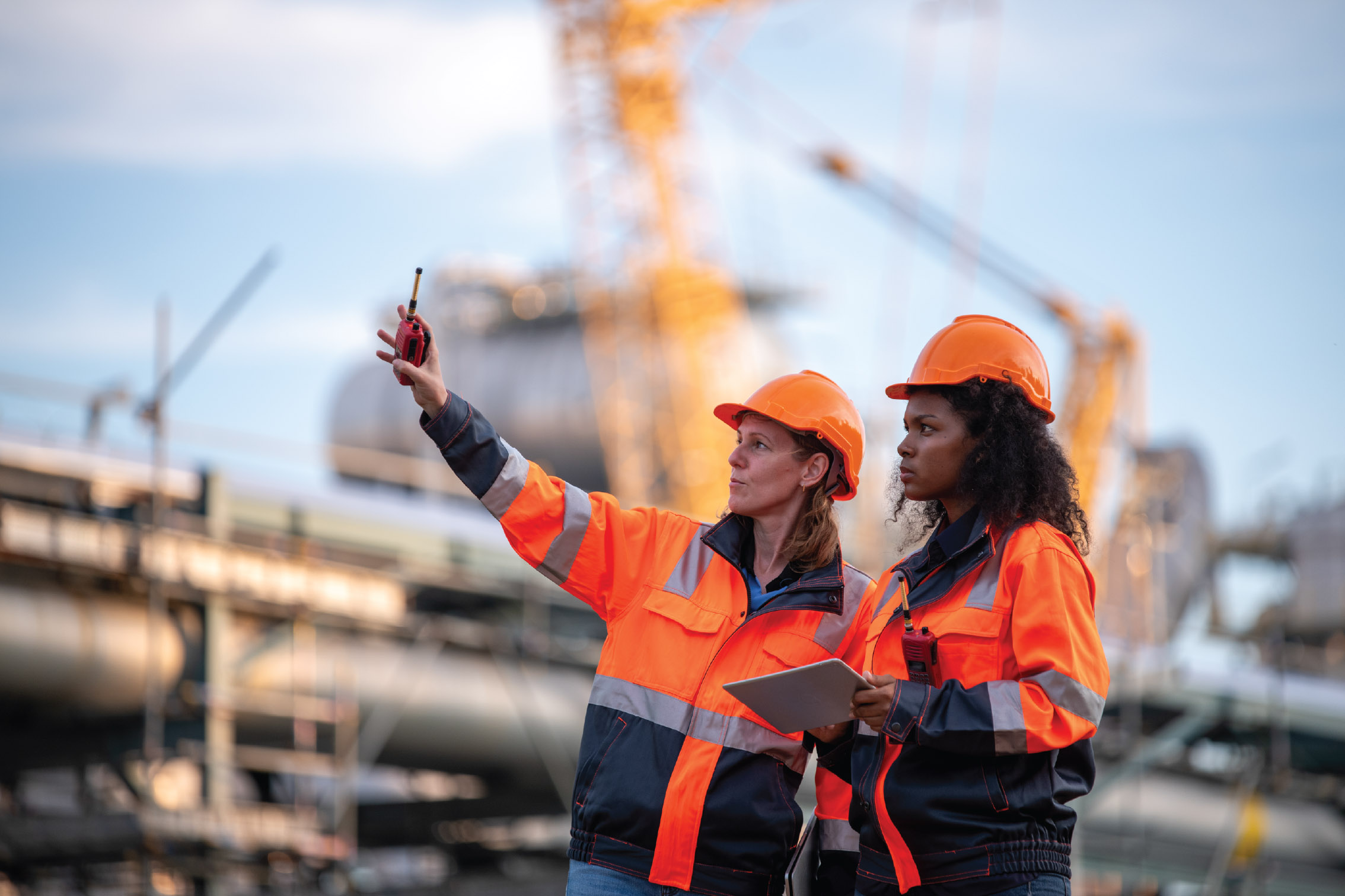 A close-up image of a contractor on-site using a tablet to log a firestopping installation with a half-built structure in the background.