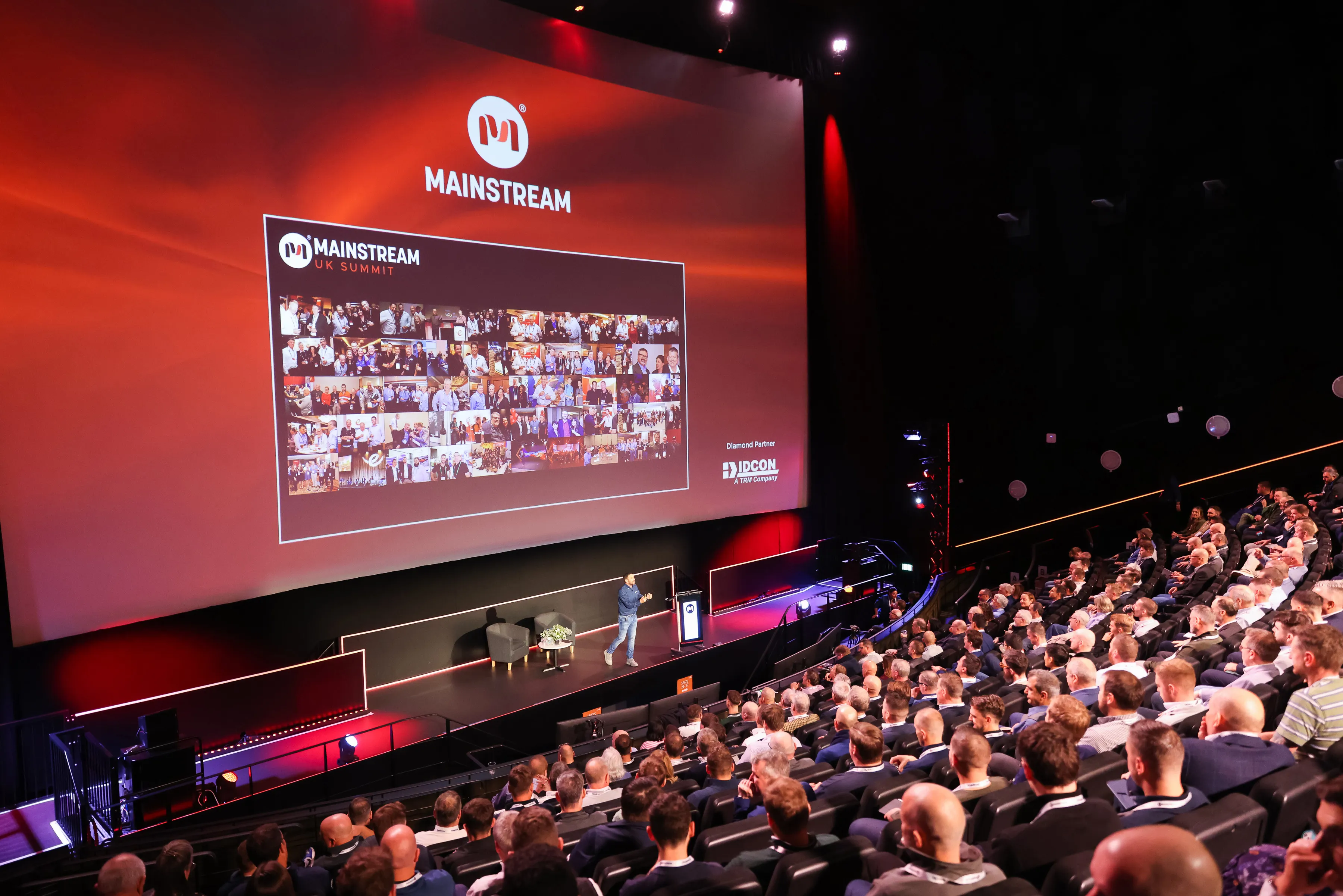 Speaker presenting on stage in front of a large audience at MAINSTREAM UK Summit