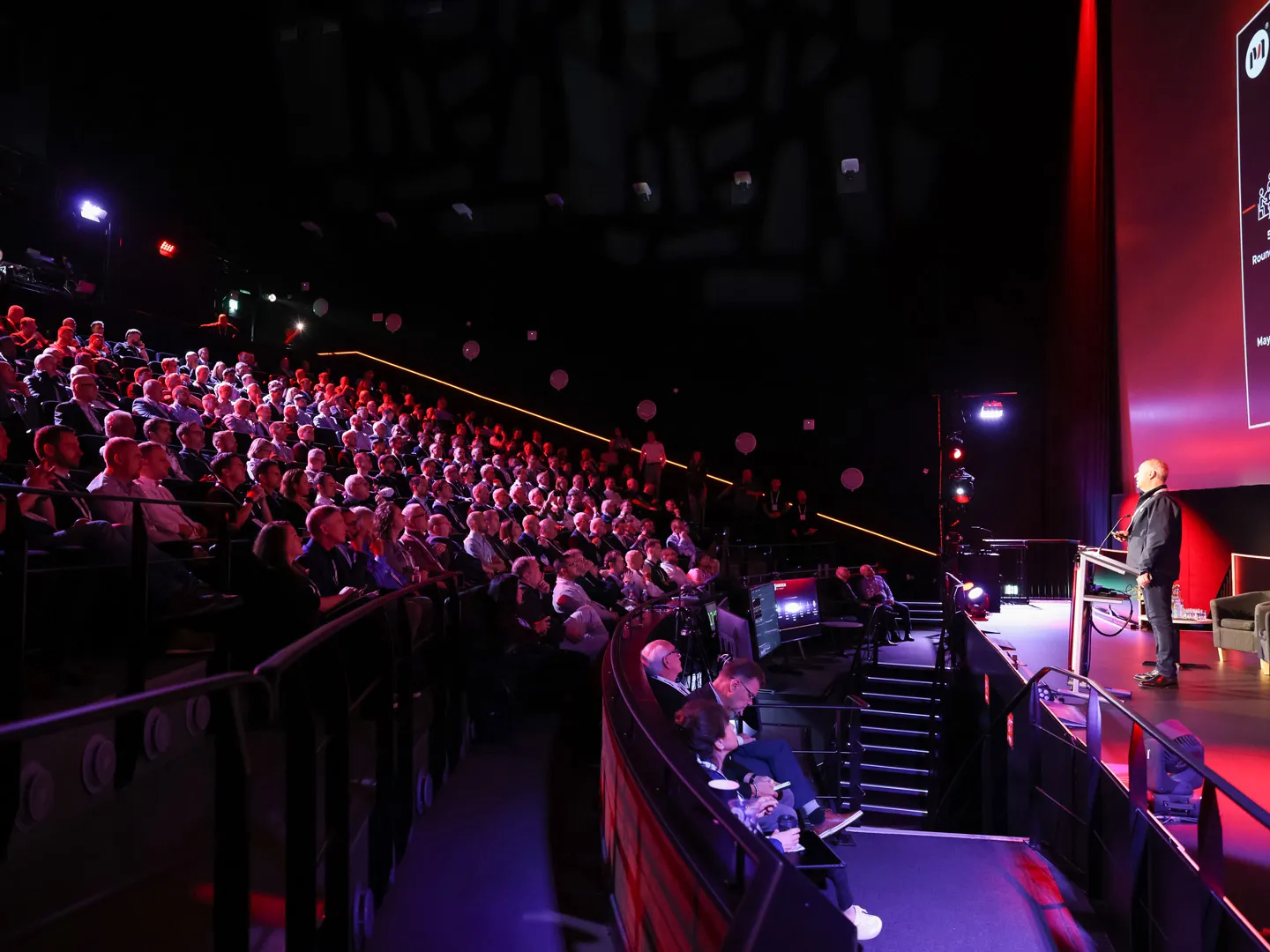 Speaker addressing a large audience seated in an auditorium at Mainstream UK Summit
