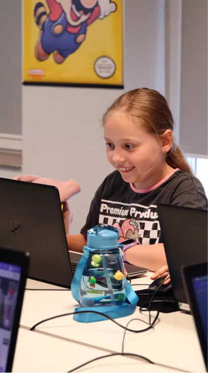 miling girl working on a laptop in a classroom
