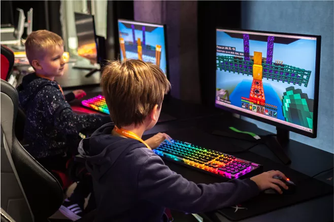 Happy boy using a desktop computer with a brightly lit keyboard.