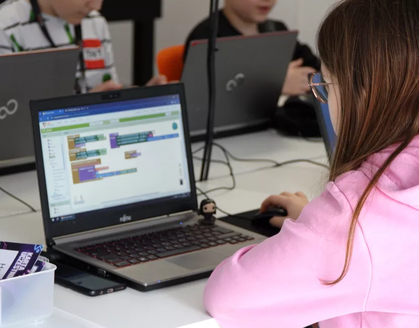 Student programming on a laptop in a classroom.