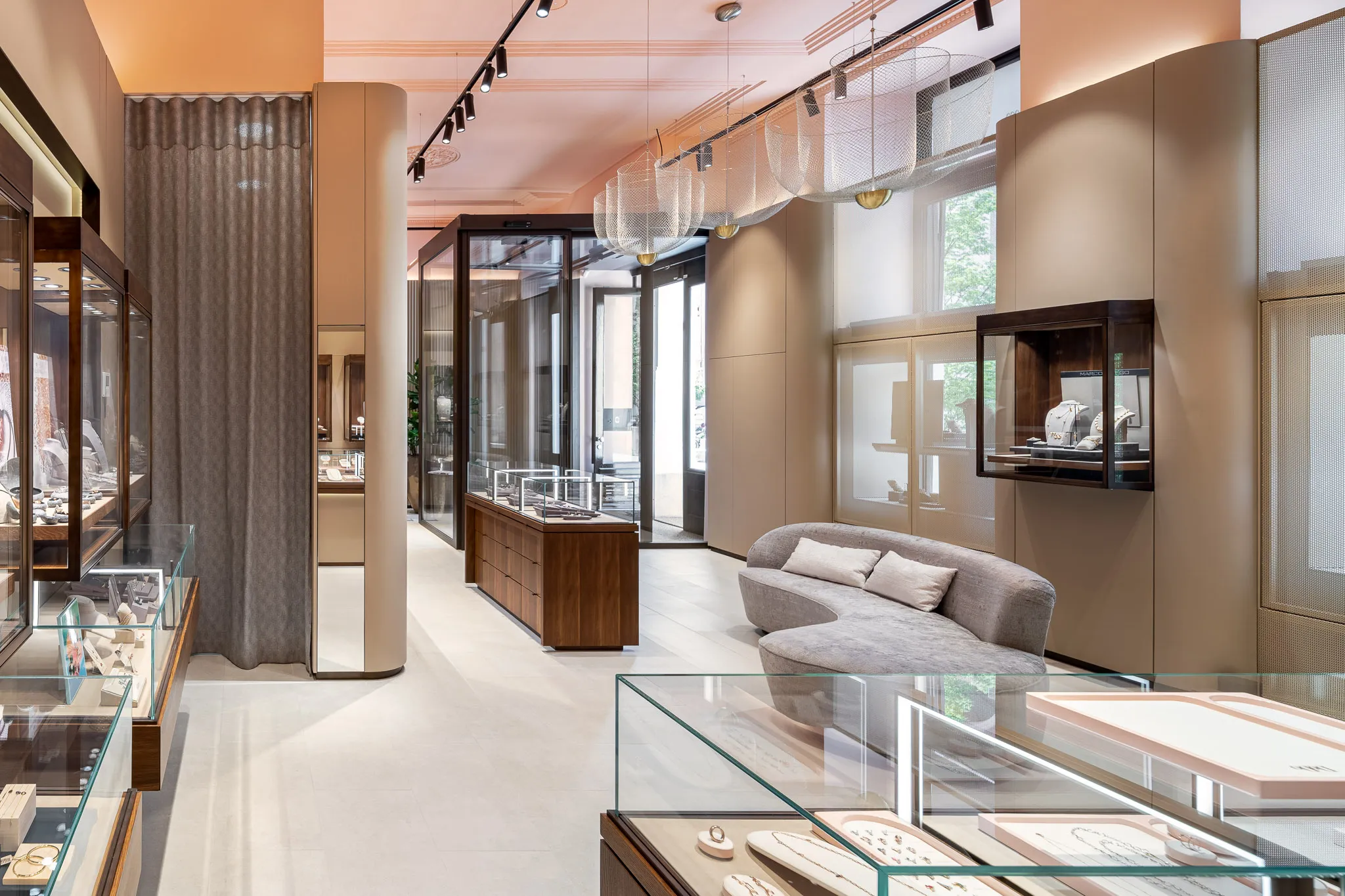 Modern interior of Malalan’s high-end jewelry store, with blush-toned ceilings, glass display islands, luxury product showcases, and a custom retail layout by Studio Mosh.