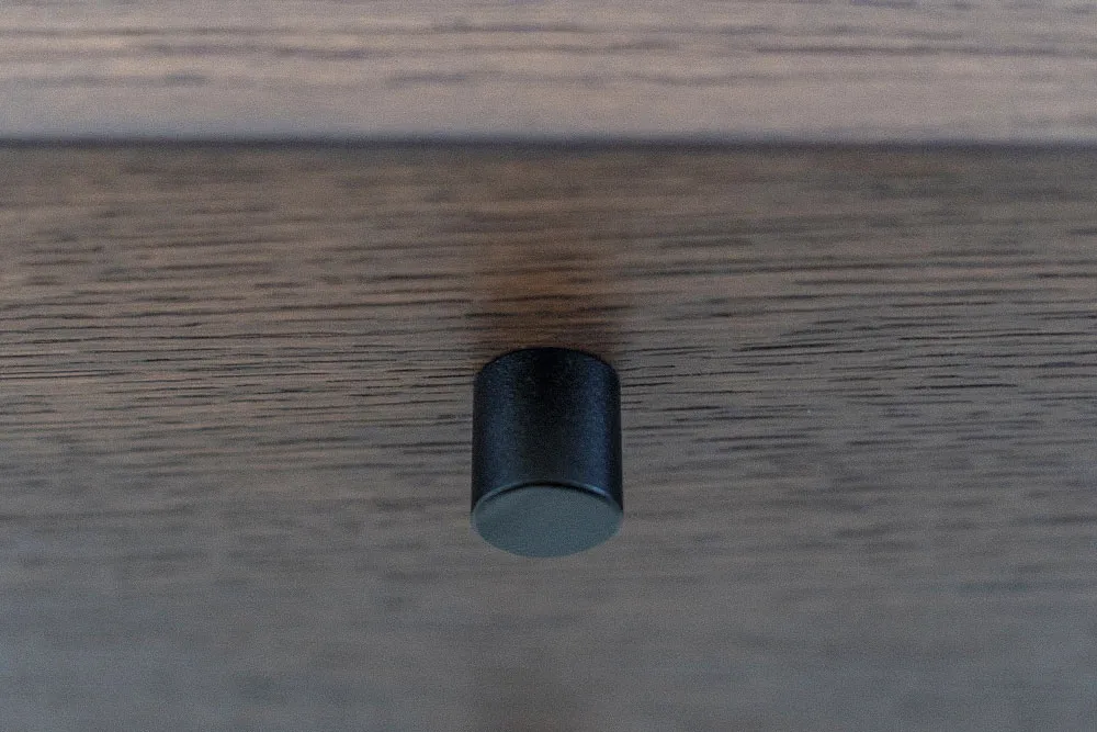 Close-up of black metal peg supporting custom floating shelves in the Modulo furniture system by Studio Mosh — a minimalist hardware detail for modern shelving design.