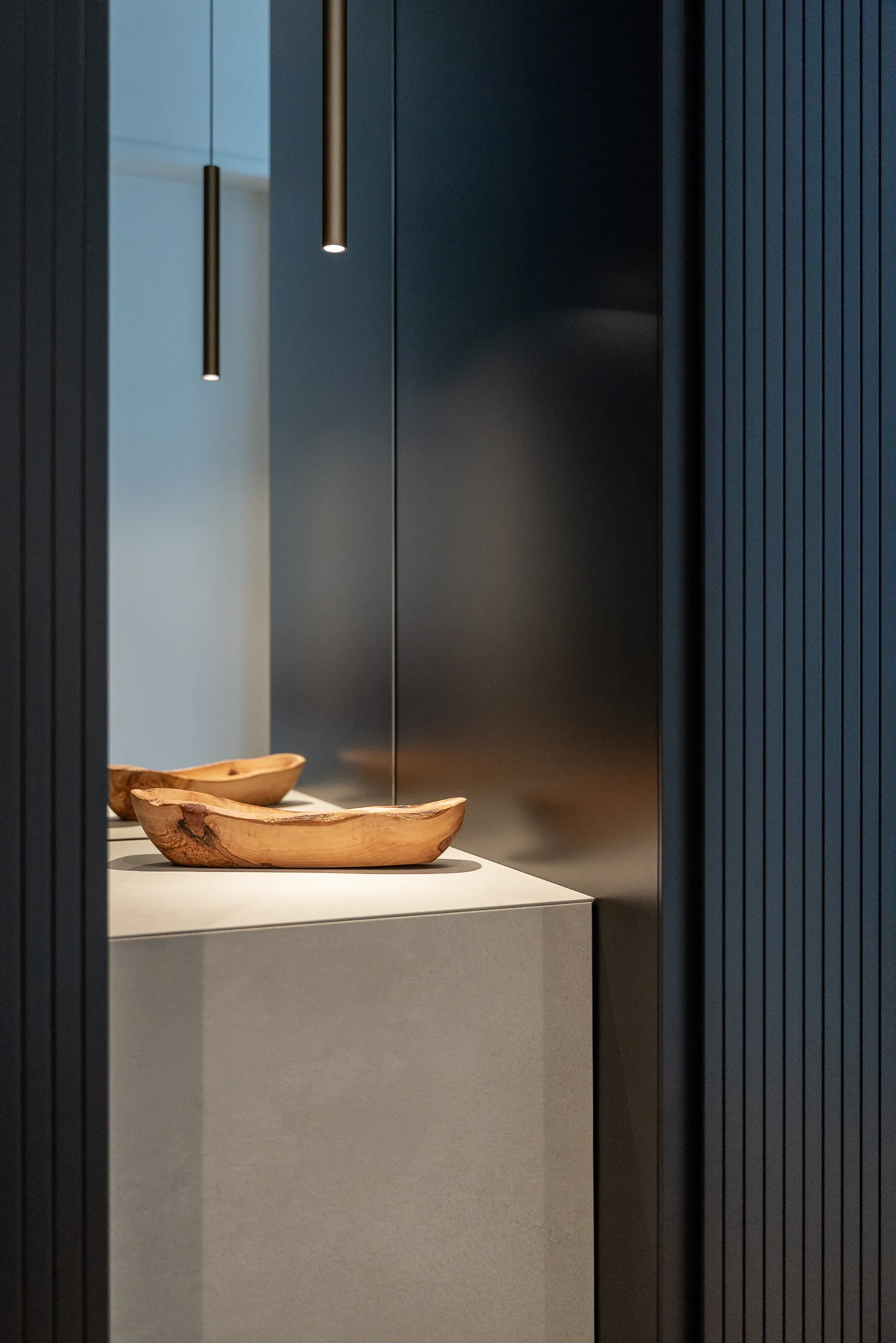 Close-up of wooden bowls under modern pendant lights in a black matte recessed niche – luxury interior decor detail.