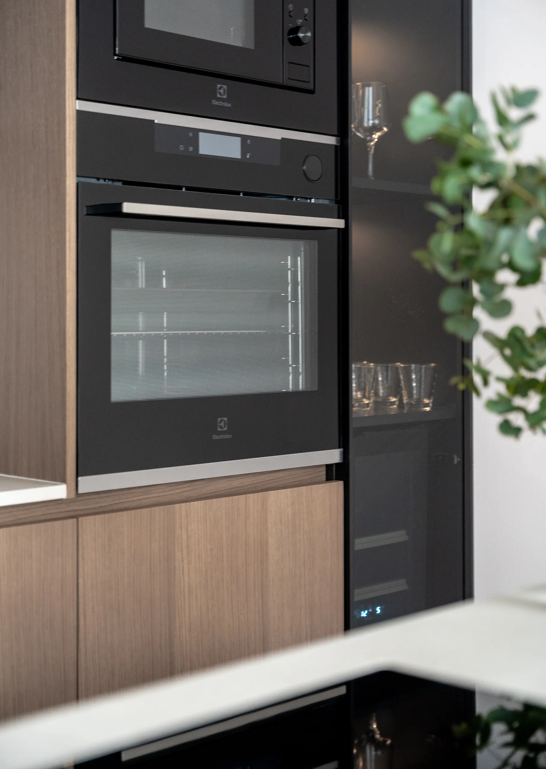 Scandinavian-inspired kitchen with clean lines, natural wood accents, and built-in black appliances – open living layout and modern finishes.