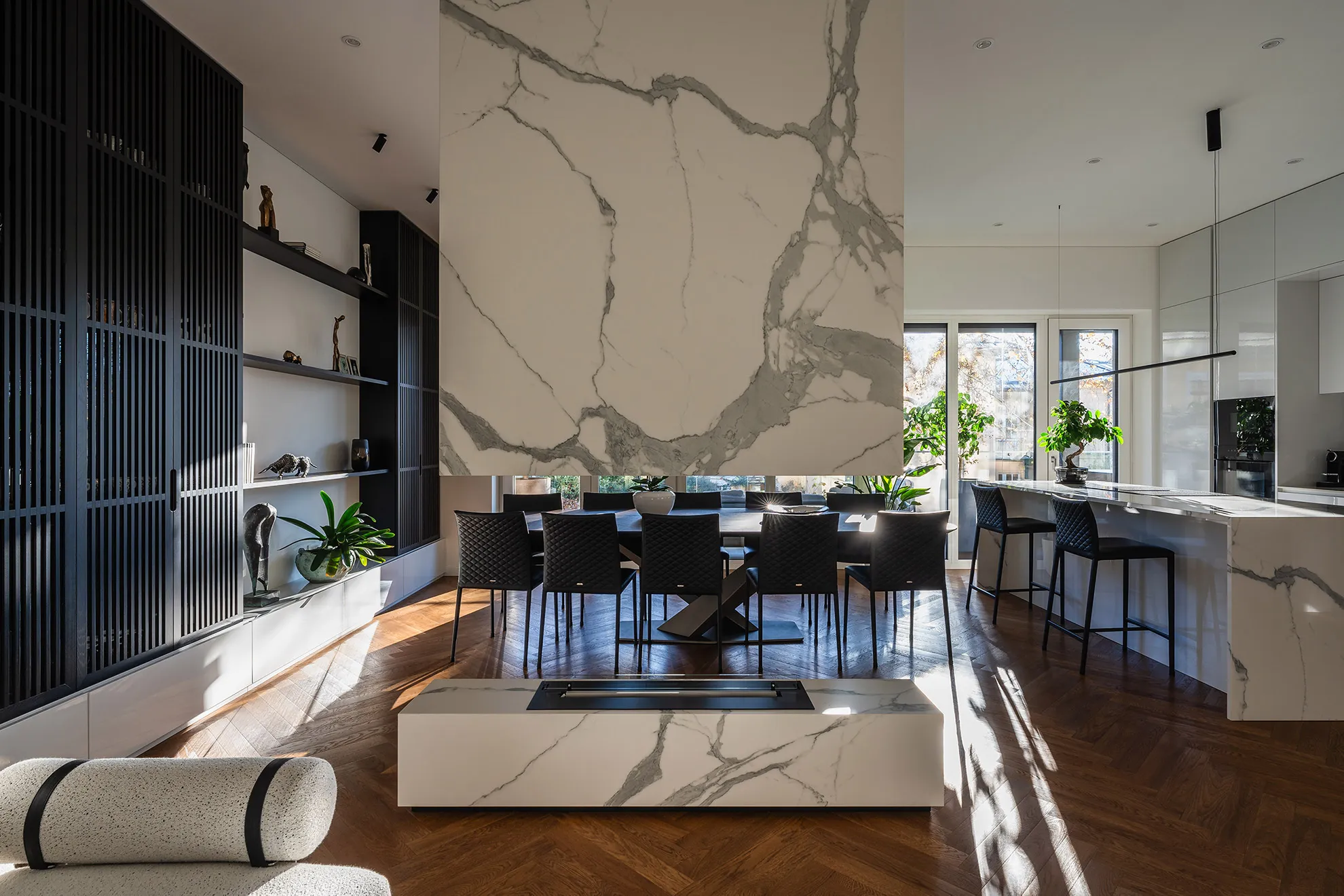 Elegant living room in Penthouse Schellenburg with a contrast of black shelving and a marble fireplace, bathed in natural light, creating a cozy yet luxurious atmosphere in Ljubljana.