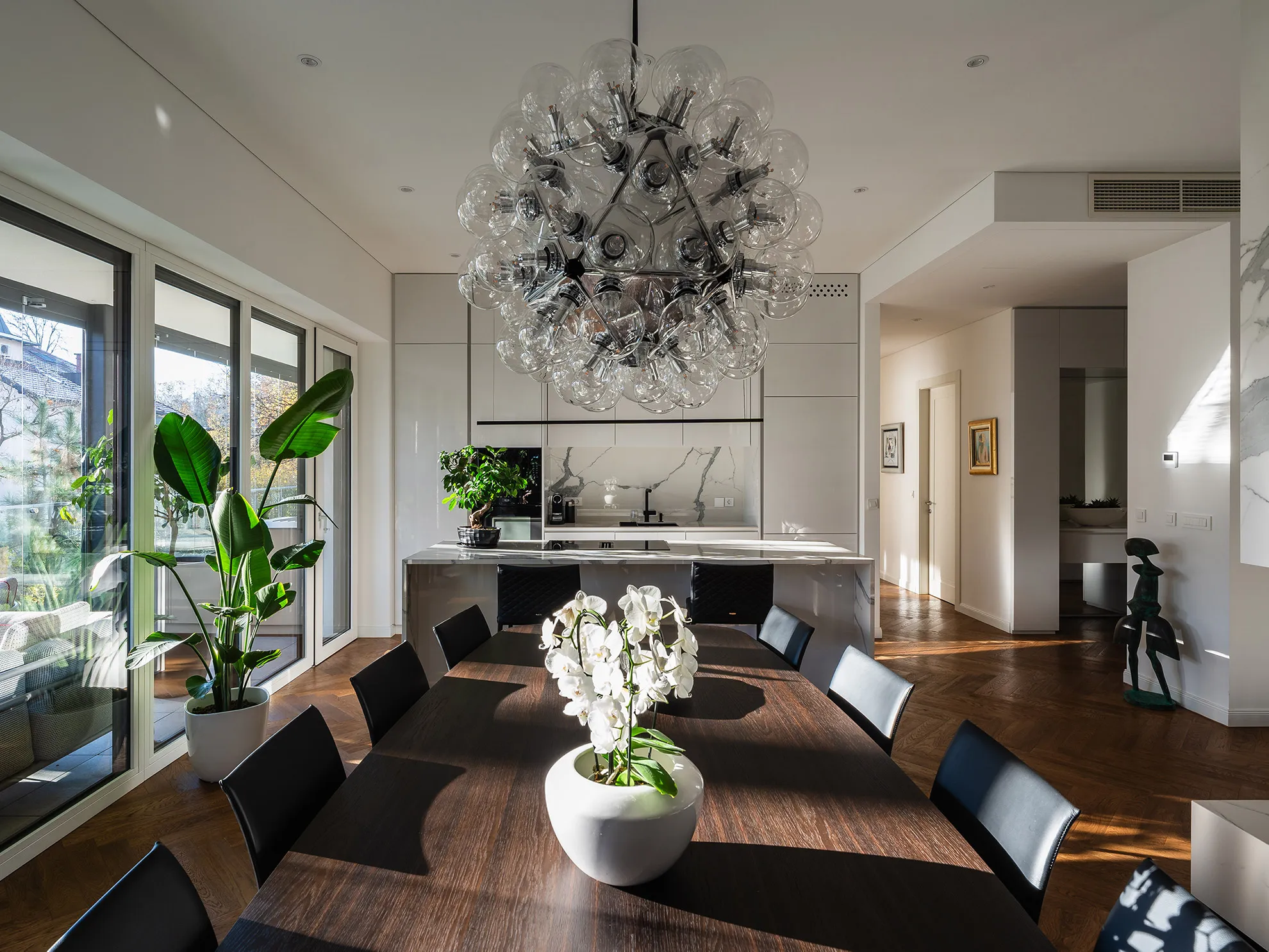 Elegant kitchen and dining area in Penthouse Schellenburg with marble countertops, sleek cabinetry, and statement lighting, designed for both cooking and entertaining in Ljubljana.