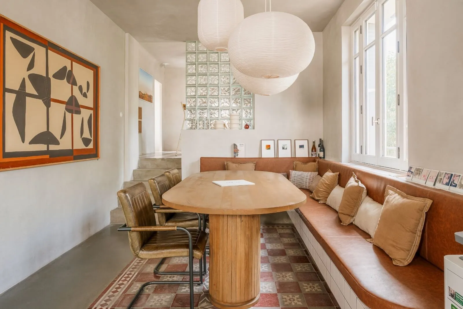 Sophisticated dining and kitchen space in a contemporary chalet interior by Studio Mosh, featuring pendant lighting, velvet dining chairs, a marble breakfast bar, and a floor-to-ceiling wine display — refined alpine living at its best.