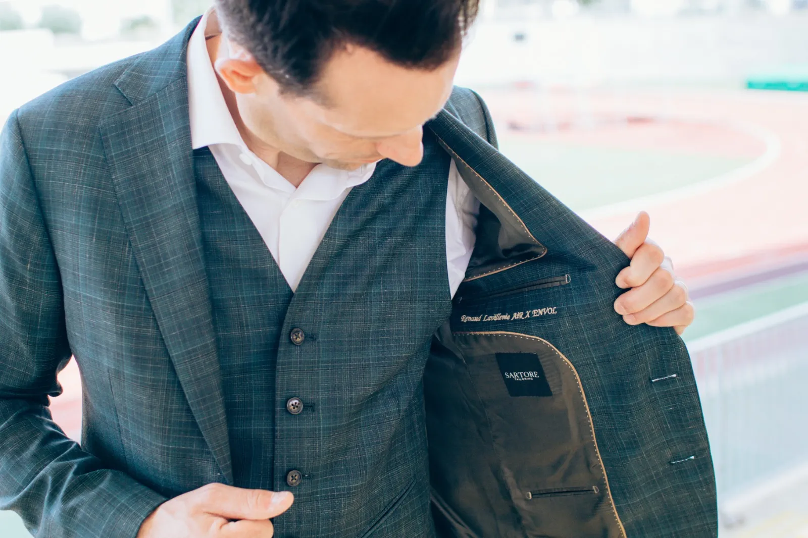 Homme ajustant son costume sur mesure vert à motif discret, montrant la doublure intérieure personnalisée signée Sartore Tailoring à Bordeaux.