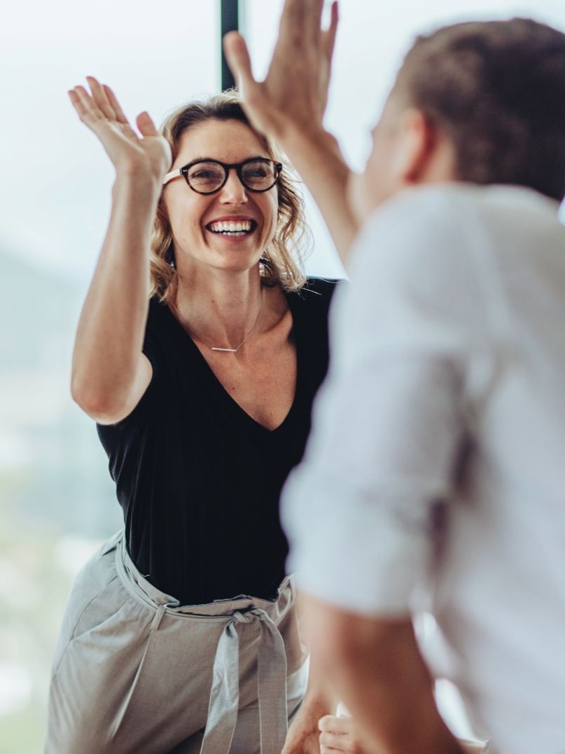 Businesswoman smiling and high-fiving a male colleague